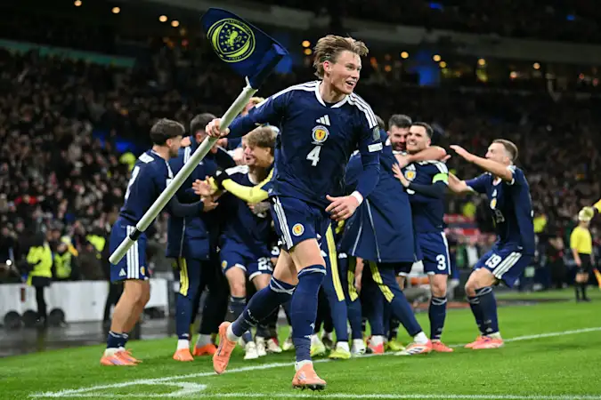Scott McTominay grabs the corner flag as Scotland's midfielder #23 Kenny McLean celebrates with teammates after scoring his long-range last-kick of the game goal during the FIFA World Cup 2026 European qualification football match
