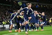Scott McTominay grabs the corner flag as Scotland's midfielder #23 Kenny McLean celebrates with teammates after scoring his long-range last-kick of the game goal during the FIFA World Cup 2026 European qualification football match