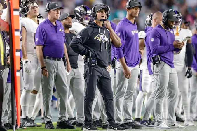 Baltimore Ravens head coach John Harbaugh standing on the sidelines next to other coaches during a game.