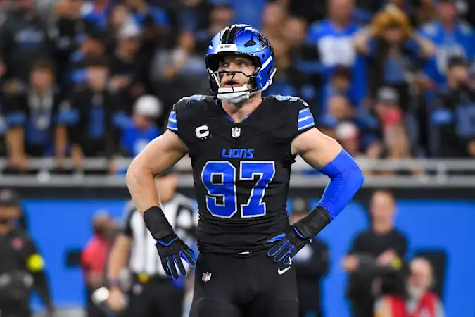 Detroit Lions defensive end Aidan Hutchinson standing on a football field with his hands on his hips.